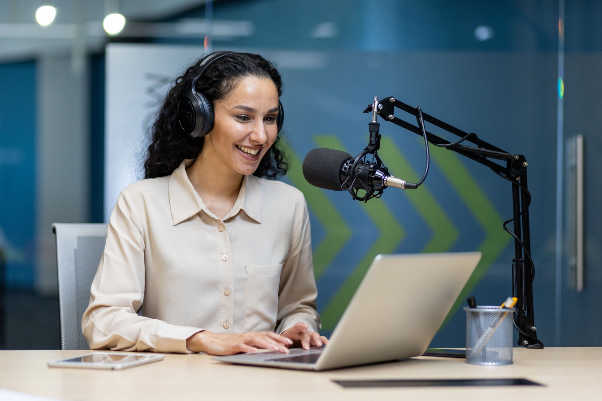 Confident woman hosting podcast with microphone and headphones in modern studio
